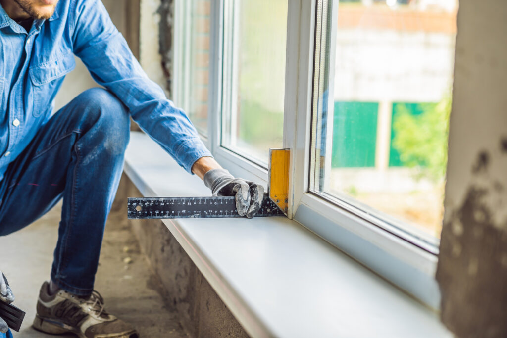 man in a blue shirt does window installation